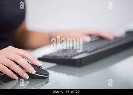 Woman using computer mouse and keyboard at desk Stock Photo
