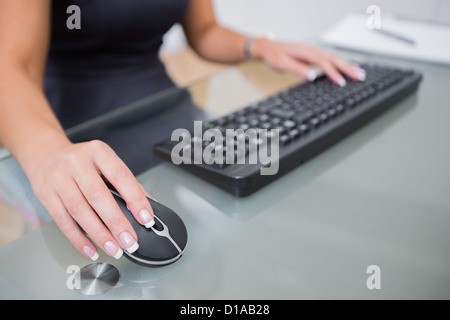 Woman using computer mouse and keyboard at desk Stock Photo