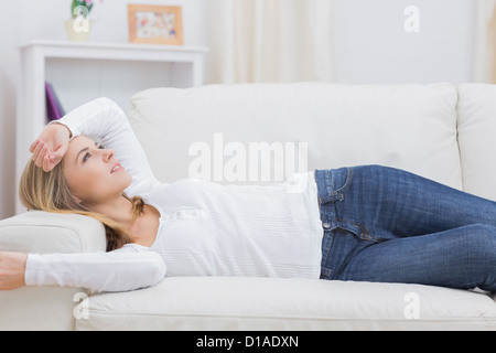 Casual thoughtful woman lying on sofa Stock Photo