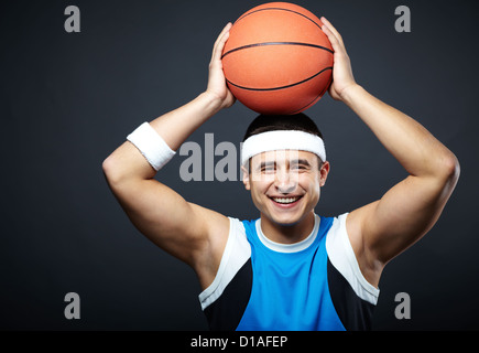 Portrait of handsome guy in sportswear with basket ball on his head looking at camera