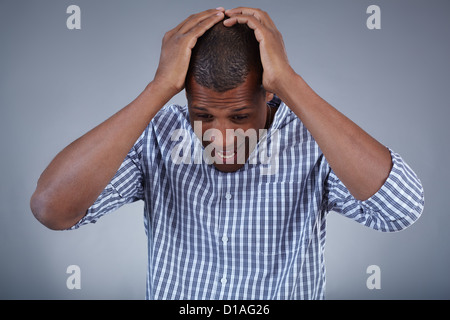 Image of young African man holding his head in astonishment Stock Photo