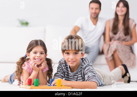 Happy siblings playing board game on floor Stock Photo