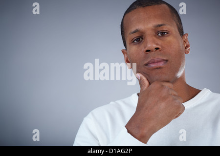 Image of young African man looking at camera with pensive expression Stock Photo