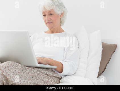 Elderly woman typing on her laptop Stock Photo