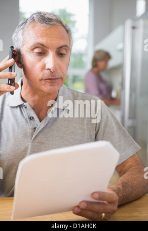 Focused mature man calling with a sheet of paper Stock Photo