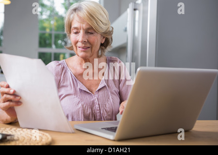 Smiling mature woman using her laptop Stock Photo