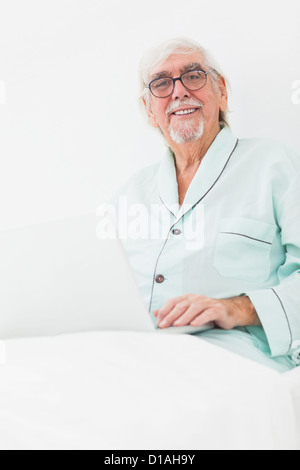 Man using laptop in bed Stock Photo