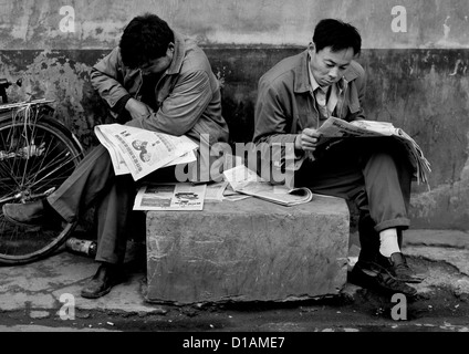 Men Reading Newspapers In A Hutong Street, Beijing China Stock Photo