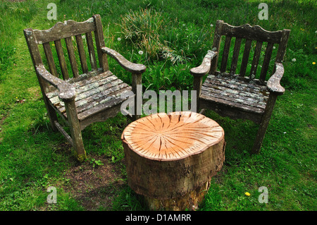 Two rustic garden seats with a wooden stump for a table UK Stock Photo