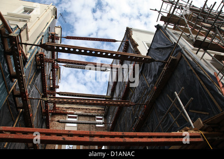 Struts to support buildings on opposite sides of a house that has been demolished for a new build. Stock Photo