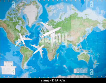Model airplanes flying in different direction over world map Stock Photo