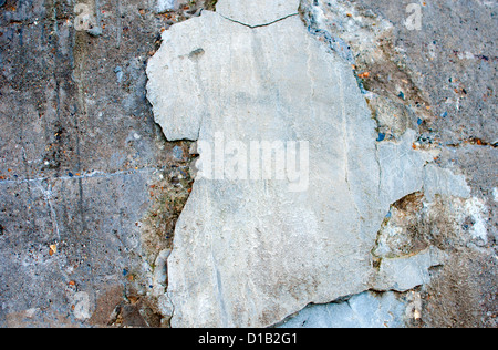 Broken grey-white plaster patch on an old cracked cement wall. Grungy background. Stock Photo