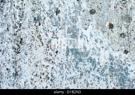 Weathered and grungy wall with patches of pale blue-grey cement showing through old paint. Stock Photo