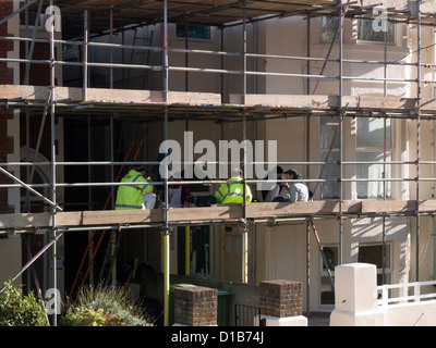 builders take a tea break sat amongst scaffolding on residential property Stock Photo