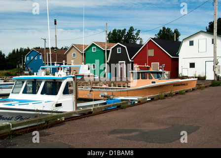 Fishboats and brightly coloured fhish houses behind them Stock Photo