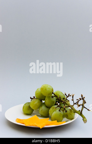 Green seedless grapes and sliced cheddar cheese on a small plate Stock Photo