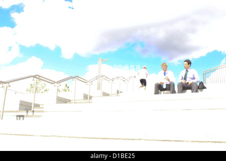 Two business men sit on some stairs outside for lunch. Stock Photo