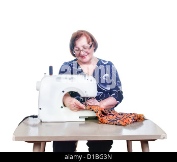 Elderly woman sews with her sewing machine. Isolated on white. Stock Photo
