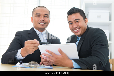 Southeast Asian business people on ebusiness activity, sitting in office. Stock Photo