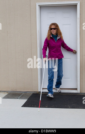 Visually impaired woman strides, cane in hand, strides confidently from her front door as she heads out for a brisk walk., Stock Photo