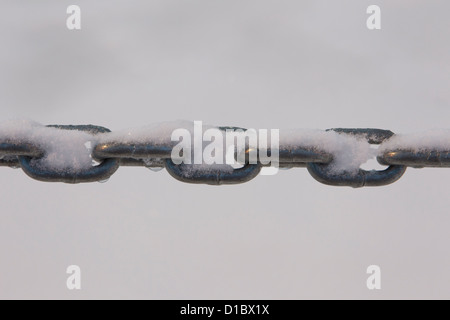 Drops of water fall from links of chain covered with melting snow. Stock Photo