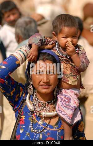 India, Rajasthan, Pushkar. A Rajasthani woman carrying her child at the Pushkar Camel Fair. Stock Photo