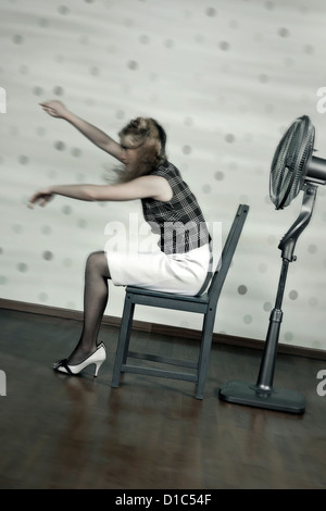 a woman is sitting in front of a fan Stock Photo