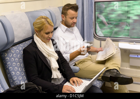 Woman with laptop man newspaper in train texting commuting reading Stock Photo