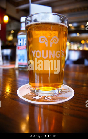 A pint of Youngs ordinary bitter ale with a bottle of HP sauce on a table in an English pub in London, the Guinea Grill, Mayfair, pub table drinks Stock Photo