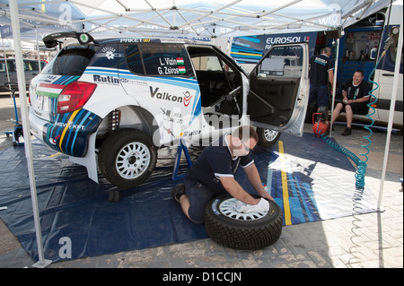 Mechanic cleaning the wheels of a Eurosol Racing team rally car in the pits at Paphos Cyprus. Cyprus Rally 2012 Stock Photo