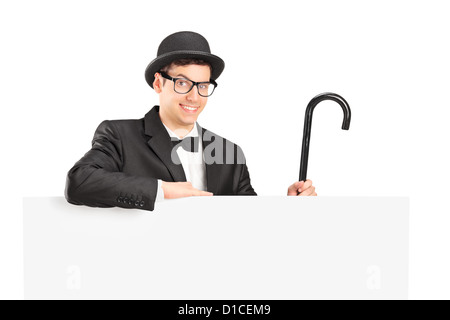 A performer in black suit, retro hat and cane posing behind a blank panel isolated on white Stock Photo