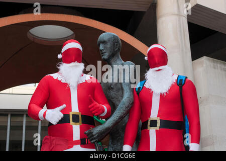 15 December 2012 London UK. Fancy dressed revellers pose with the bronze Dame Elizabeth Frink sculpture 'Shepherd and Sheep' in Paternoster Square during Santacon 2012. The annual celebration of all things Christmas which sees people dressed as Santa as well as elves, reindeer and Christmas trees has been running for twelve years. Stock Photo