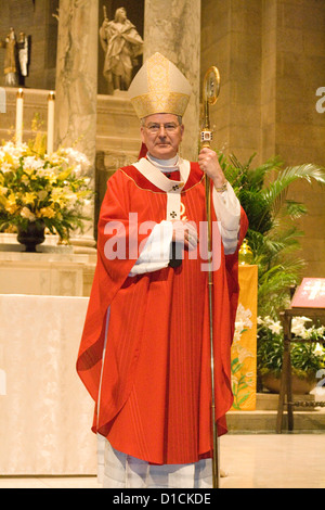 Catholic Priest wearing red vestments presiding over confirmation Mass. Basilica of 'St Mary' Minneapolis Minnesota MN USA Stock Photo