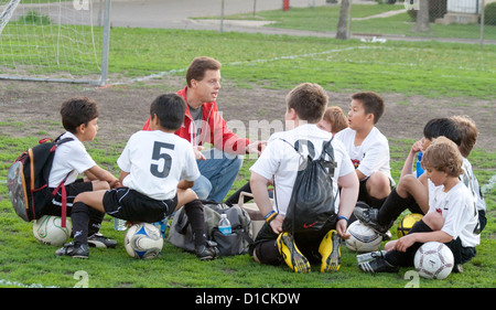 Coach discussing soccer game strategy with boys age 10 during a rest break. Monroe Memorial Park St Paul Minnesota MN USA Stock Photo