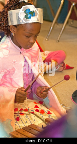 African American student playing xylophone wearing a recycling hat during a program. Horace Mann School St Paul Minnesota MN USA Stock Photo