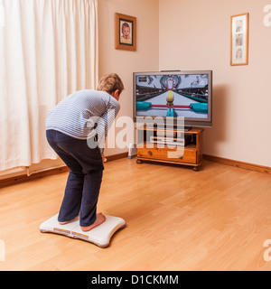 A 9 year old boy playing on a Nintendo Wii Fit board Stock Photo