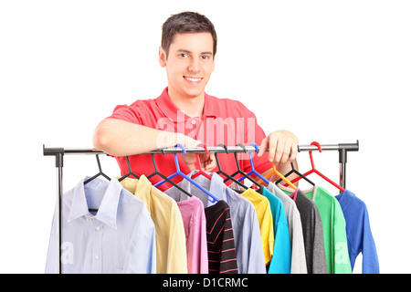 A smiling guy posing on a hang rail full of clothes isolated on white background Stock Photo
