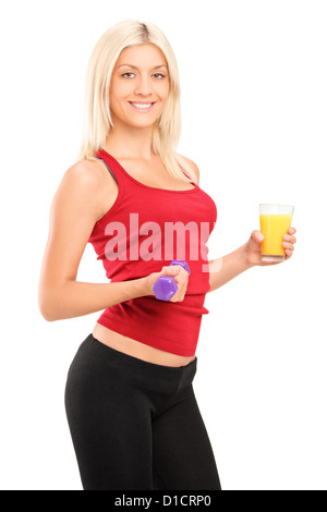 An attractive female athlete holding a dumbbell and glass of orange juice isolated on white background Stock Photo