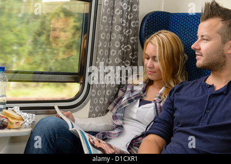 Woman reading magazine man looking train window happy travel vacation Stock Photo