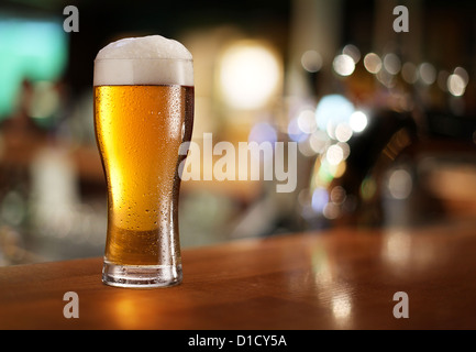 Glass of light beer on a dark pub. Stock Photo