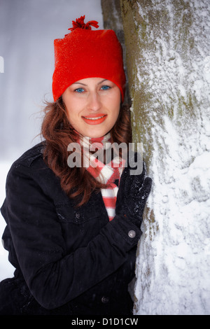 Young woman leaning against a tree during winter outdoor. Stock Photo