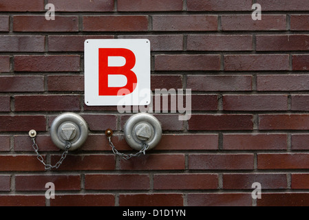 Wall mounted fire hydrant for emergency use with Dutch fire sign Stock Photo