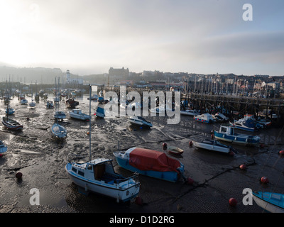 Pleasure craft on the mud at low tide in Scarborough harbour North Yorkshire UK on a misty winter afternoon Stock Photo