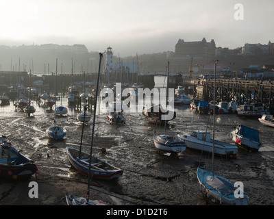Pleasure craft on the mud at low tide in Scarborough harbour North Yorkshire UK on a misty winter afternoon Stock Photo