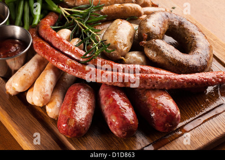 Assortment of grilled sausages on a wooden board. Stock Photo