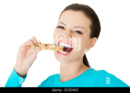 Young woman eating Cereal candy bar, isolated on white  Stock Photo