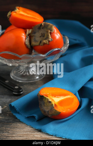 Persimmons in vase on wooden table