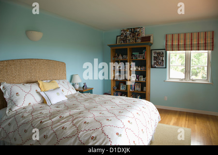 Bed with floral print comforter in blue bedroom; Carpinteria; California; USA Stock Photo