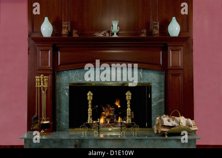 FIREPLACES cherry wood mantel and green marble surround brass fireplace tools andirons and log  carrier green symmetric vases Stock Photo