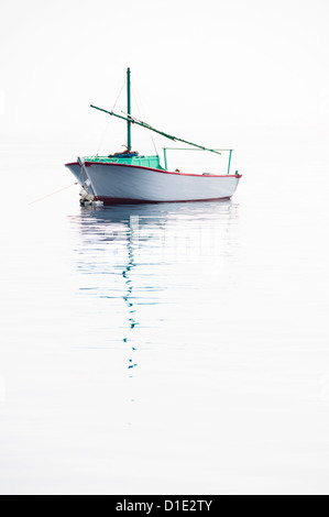 Lonely small fishing boat on very calm sea with smooth surface flowing together with sky Stock Photo